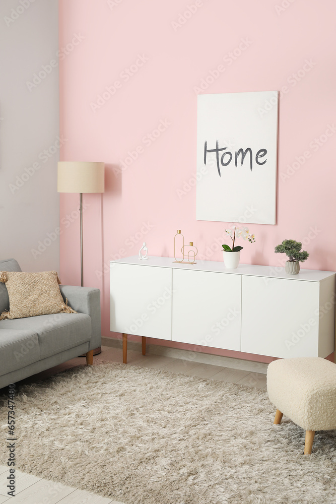 Interior of living room with cozy grey sofa, white cabinet and poster