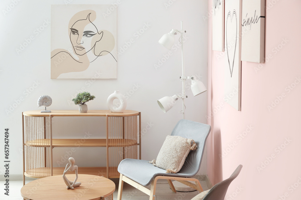 Interior of living room with cozy grey armchairs, coffee table, shelving unit and different paintings