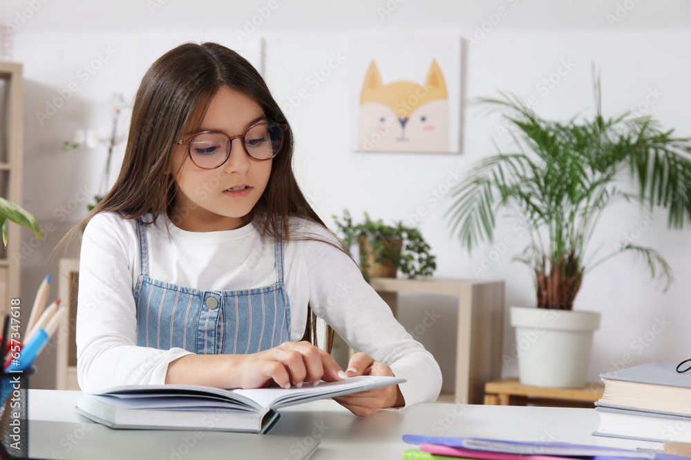 Little girl reading schoolbook at home