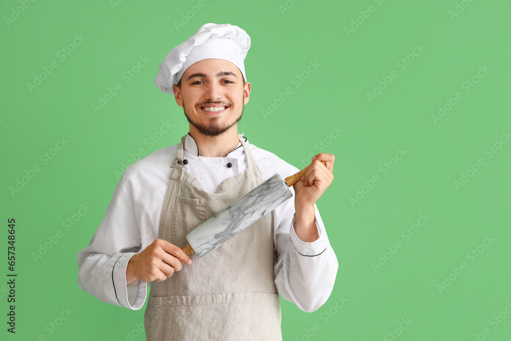 Male chef with rolling pin on green background