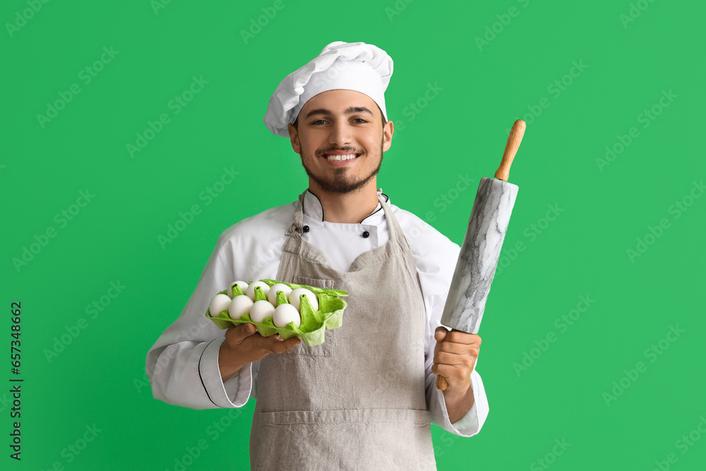 Male chef with eggs and rolling pin on green background