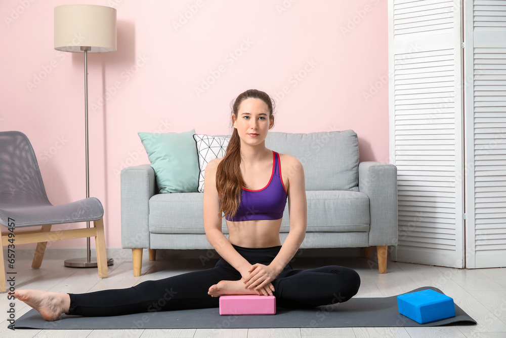 Sporty young woman practicing yoga with block at home