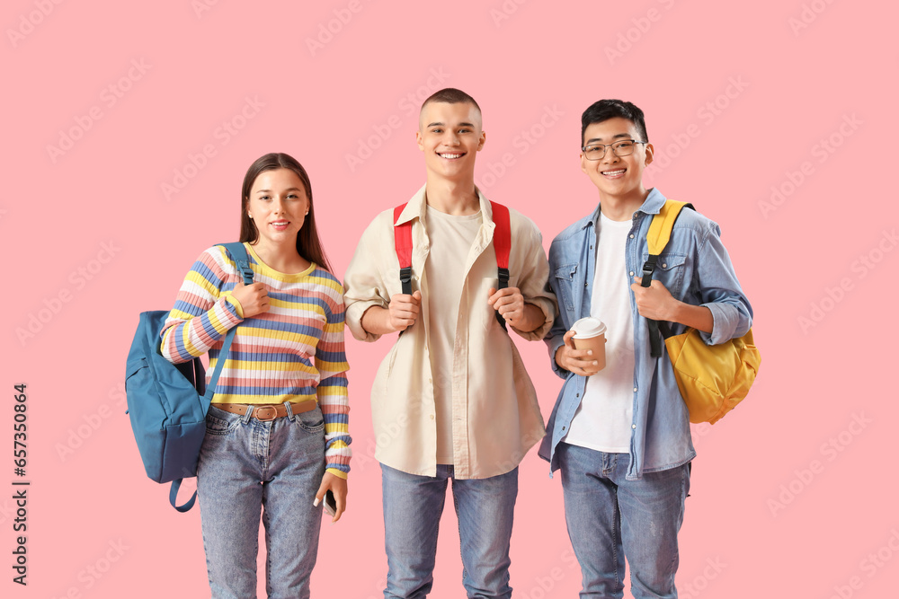 Happy students with backpacks and cup of coffee on pink background