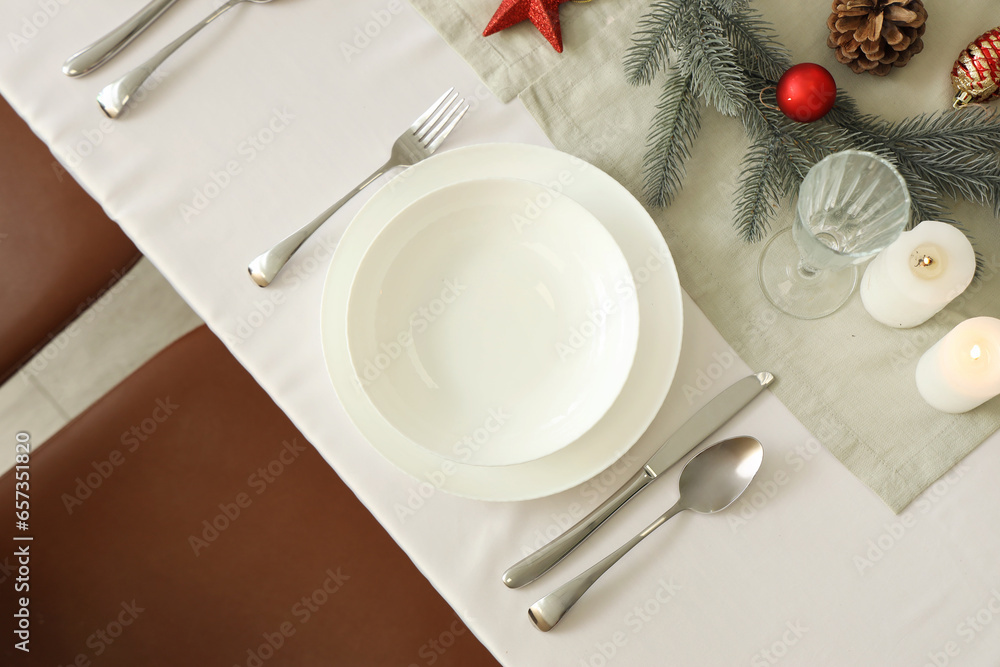 Festive table setting with white plates, cutlery and Christmas decorations