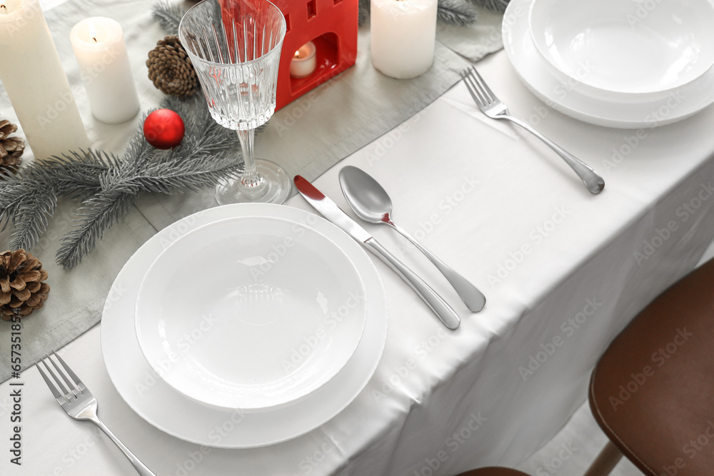 Festive table setting with white plates, cutlery and Christmas decorations