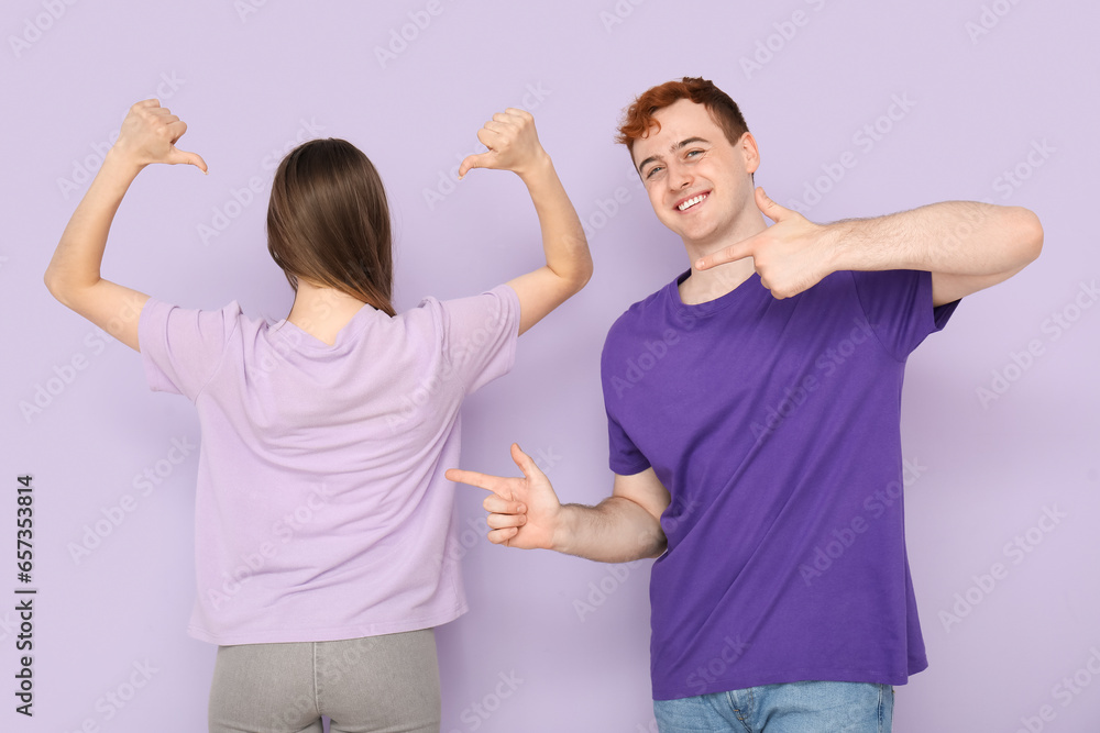 Young couple in t-shirts on lilac background