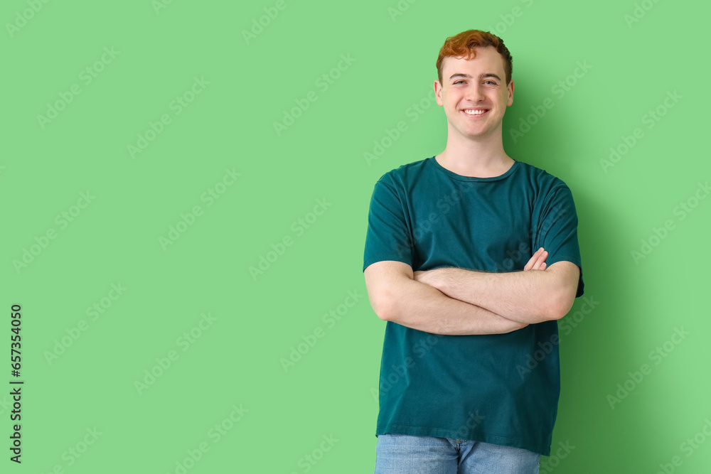 Young man in t-shirt and with crossed arms on green background