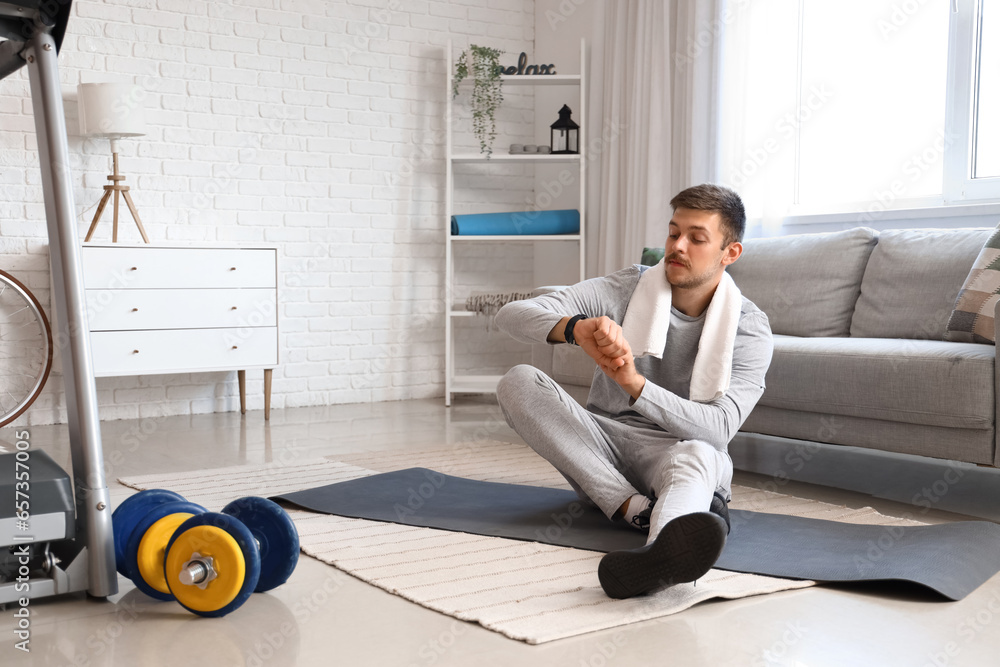 Sporty young man with fitness tracker at home