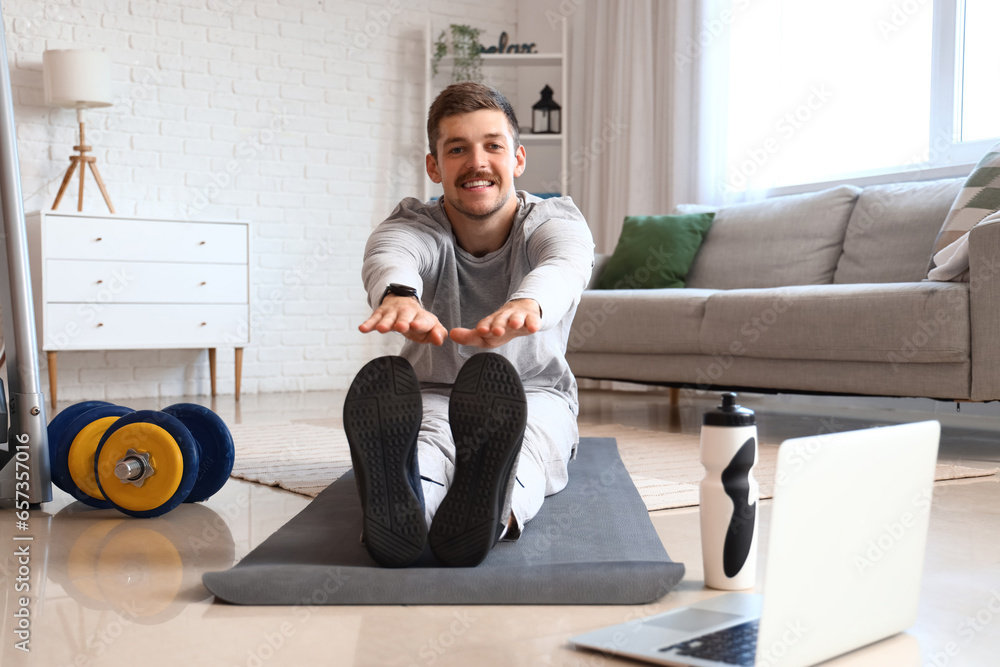 Sporty young man stretching at home. Online training concept