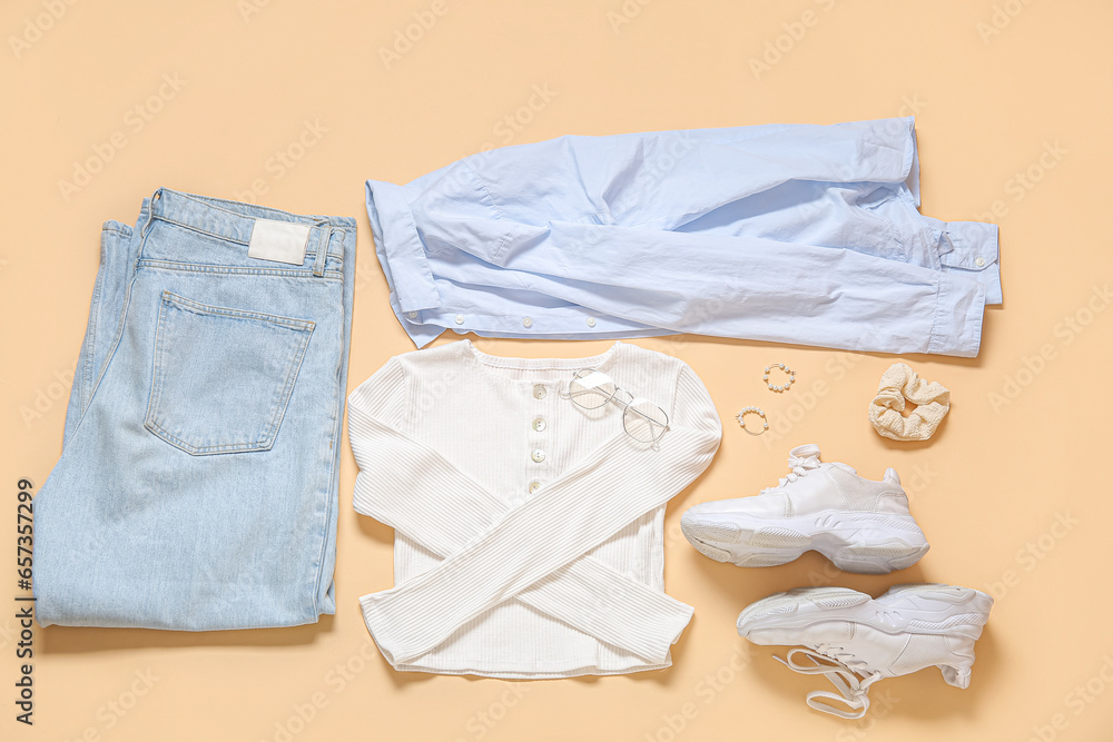 Set of stylish female clothes with sneakers and accessories on color background