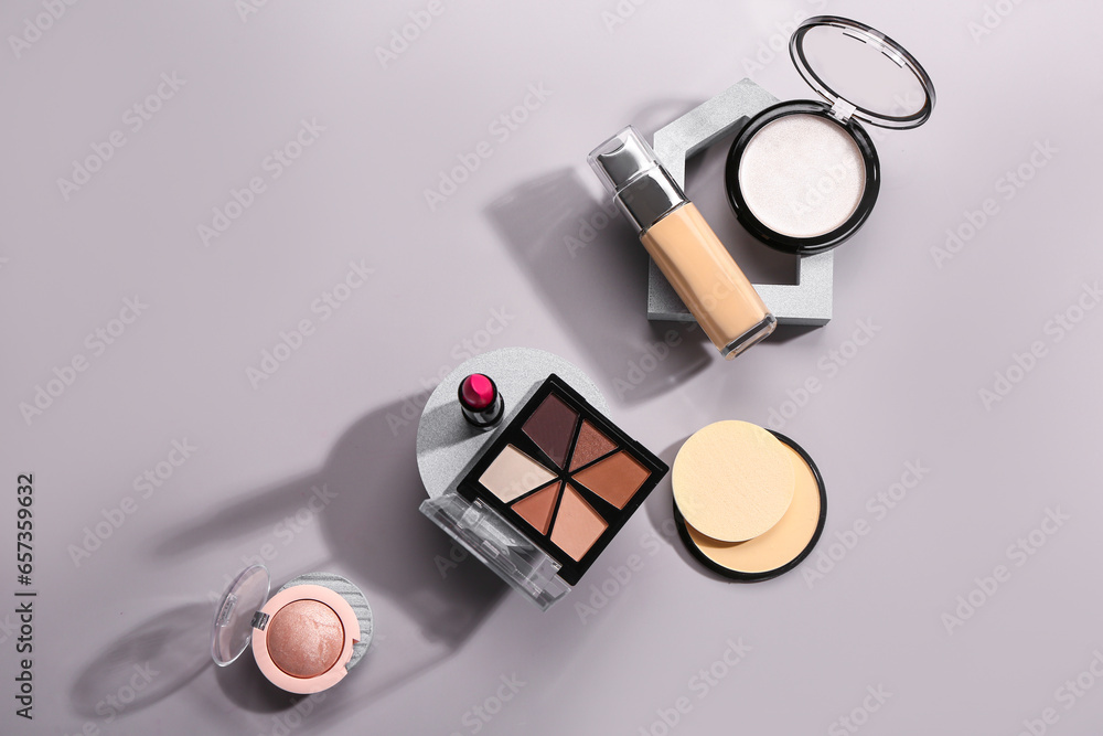 Stands with different decorative cosmetics on grey background