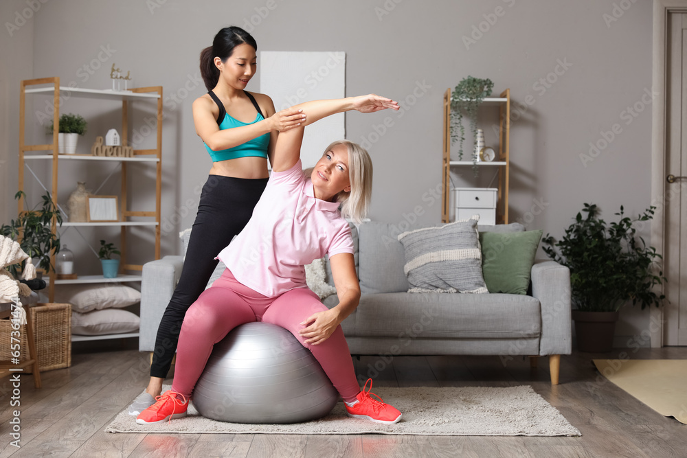 Mature woman on fitball training with rehabilitation therapist at home