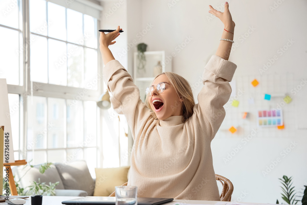 Happy female interior designer working at table in office