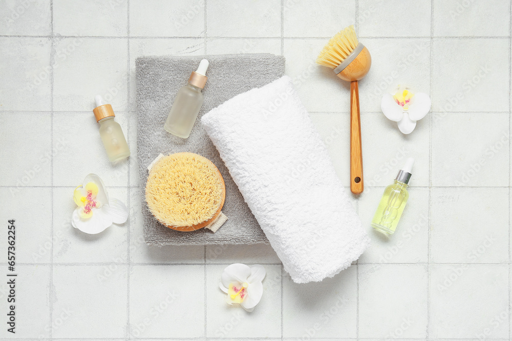 Composition with spa accessories, bottles of essential oil and orchid flowers on light tile background