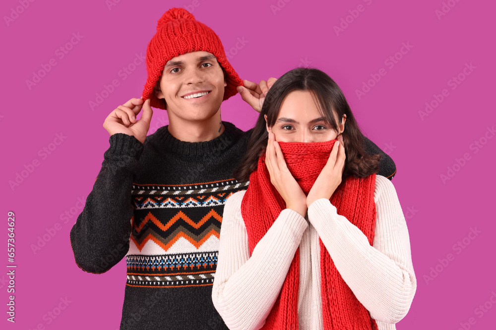 Happy young couple in warm clothes on purple background