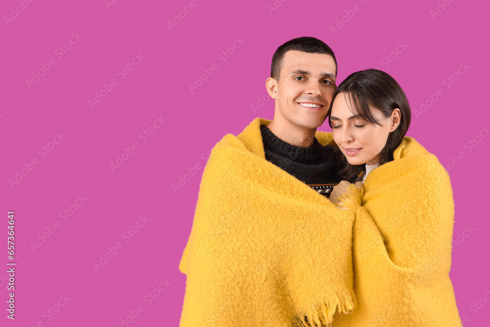 Happy young couple with plaid on purple background