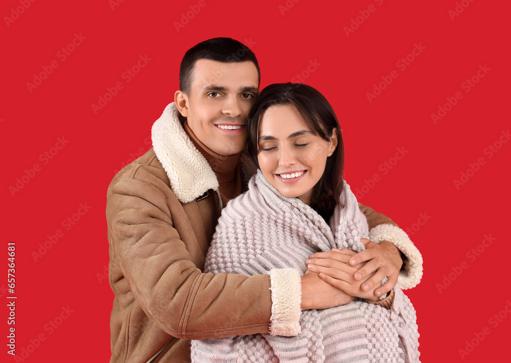 Happy young couple with plaid on red background