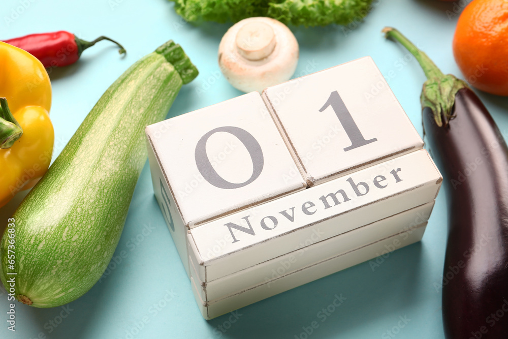 Fresh vegetables, fruits and cube calendar with date NOVEMBER 1 on blue background. World Vegan Day concept