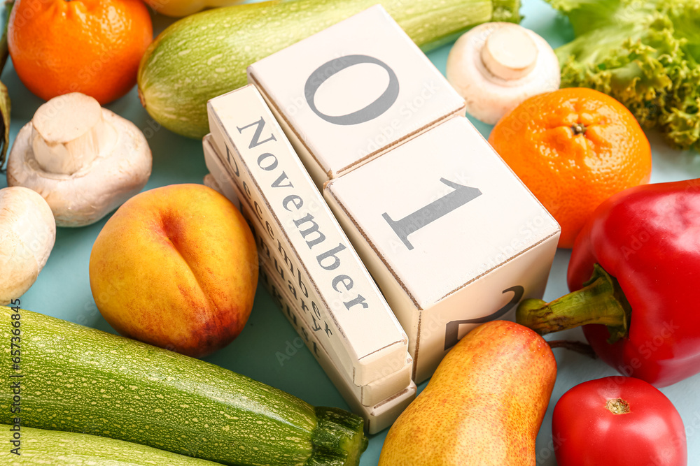 Fresh vegetables, fruits and cube calendar with date NOVEMBER 1 on grey background. World Vegan Day concept