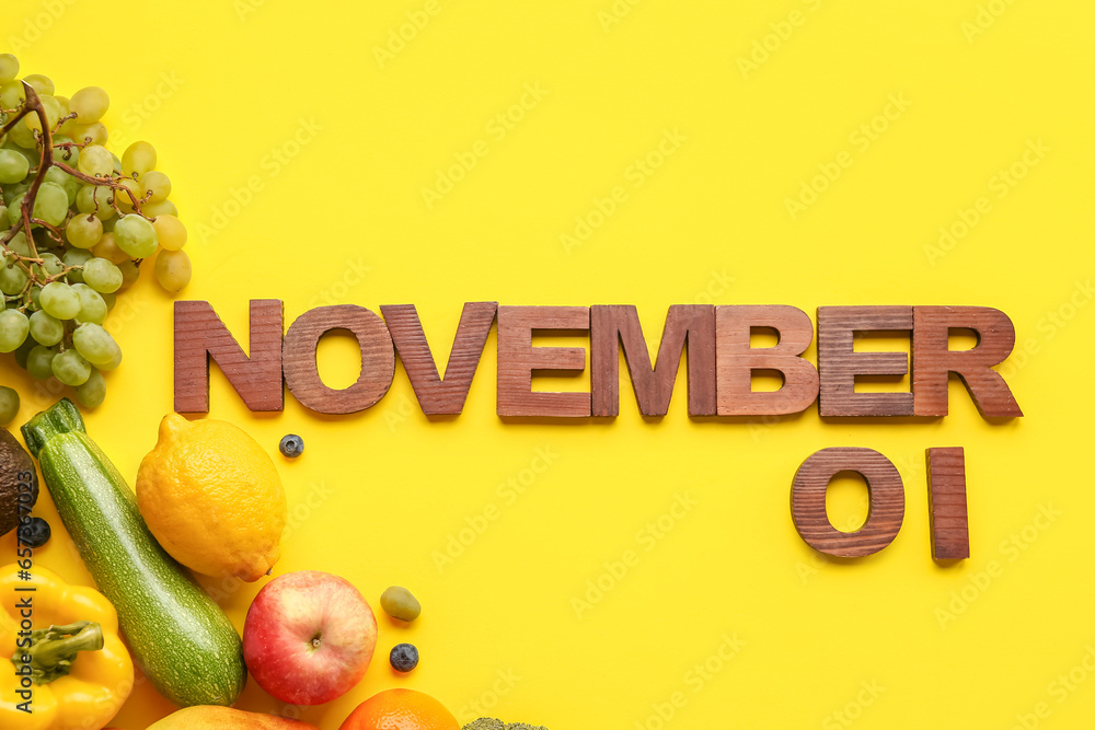 Date NOVEMBER 1 made of wooden letters with fresh vegetables and fruits on yellow background. World Vegan Day concept