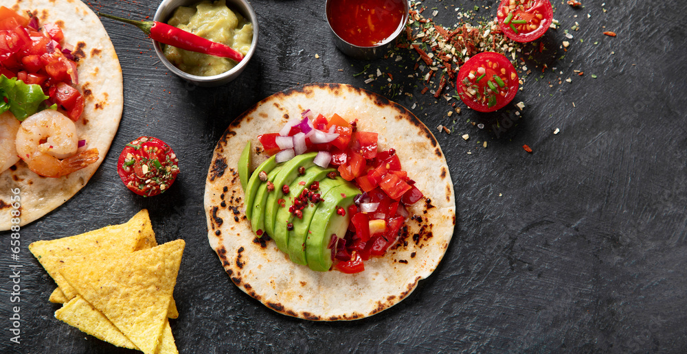 Tacos with salsa, vegetables and avocado on black background