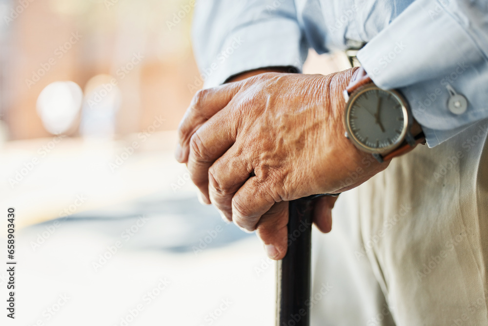 Senior, hands and stand with cane in closeup for retirement, vacation or trip on blurred background. Elderly, person and wrinkles with health, medical care or wellness in rehabilitation for injury