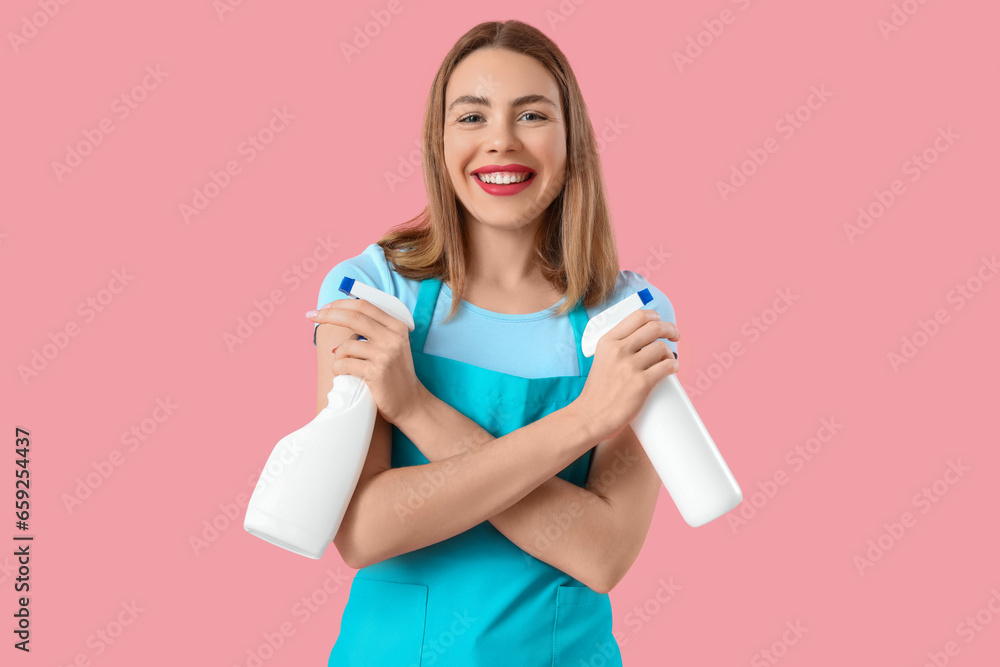 Young woman with spray bottles of detergent on pink background