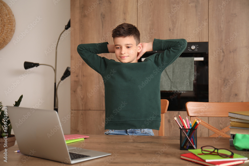 Little boy studying online with laptop in kitchen