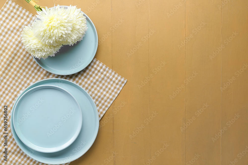 Clean plates and chrysanthemum flowers on wooden table