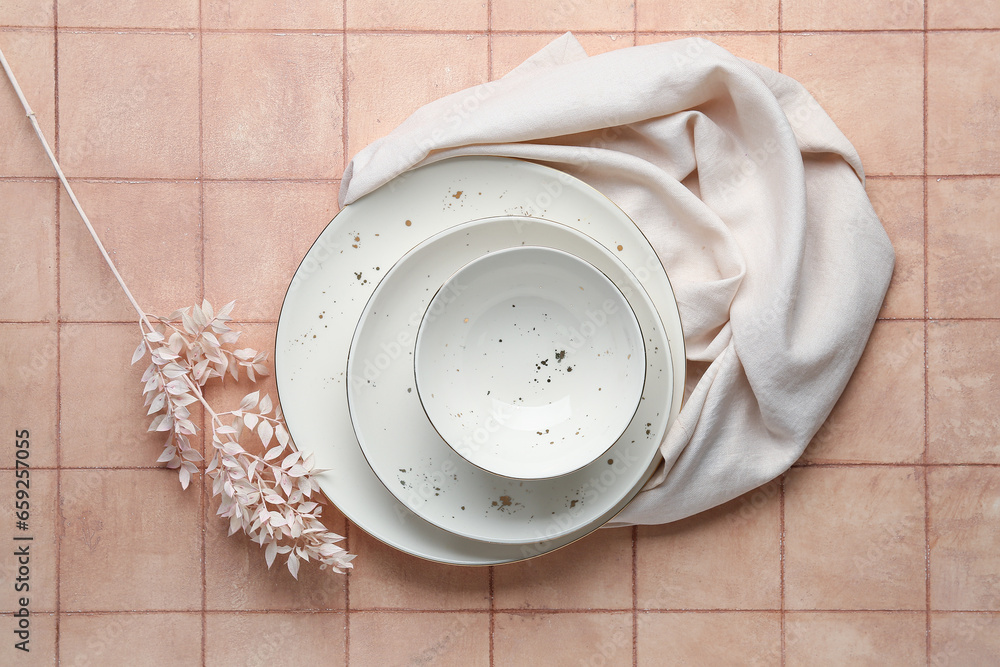 Clean white plates and bowl with floral decor on pink tiled table