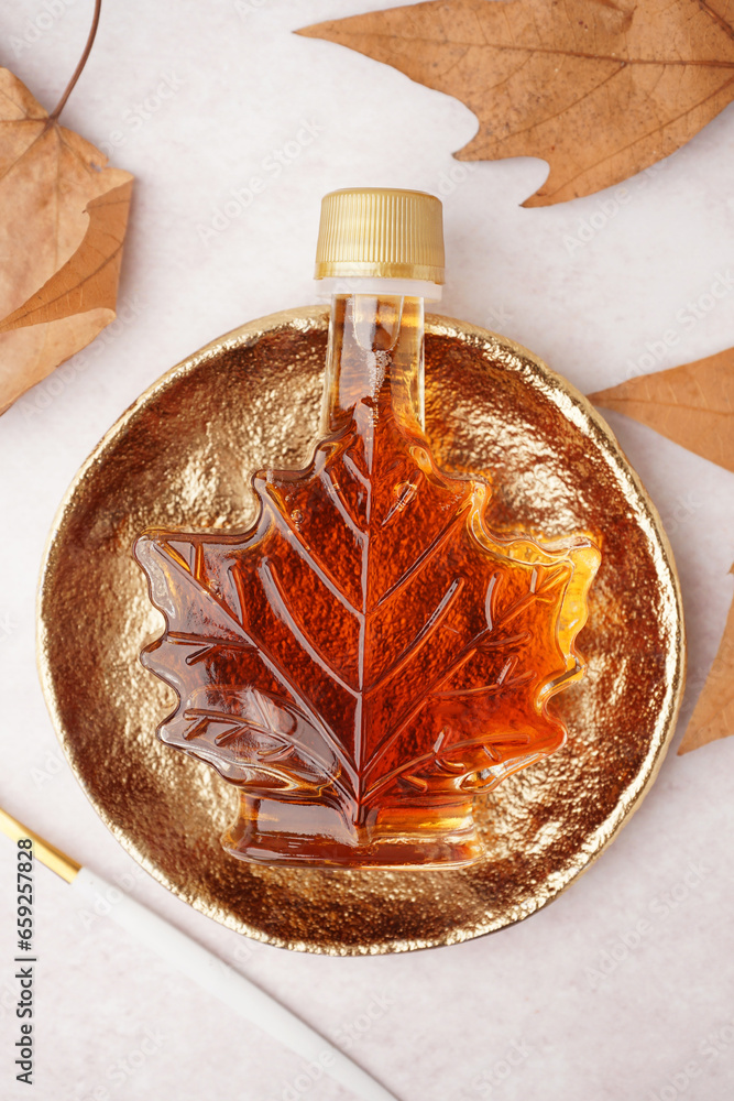 Bottle of tasty maple syrup on light background