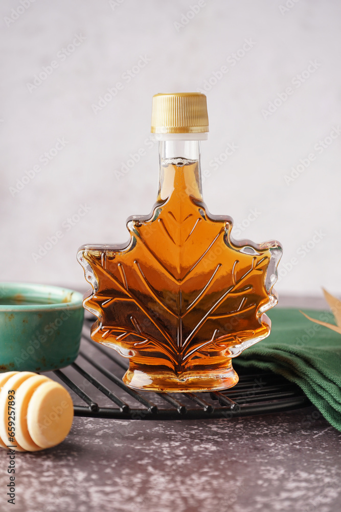 Bottle of tasty maple syrup on table