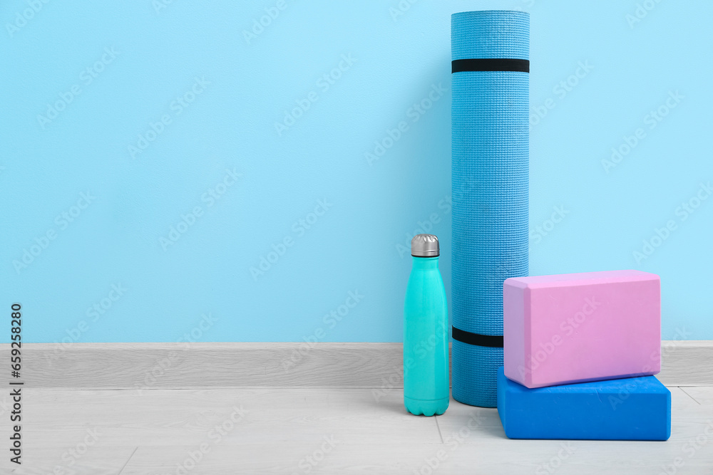 Yoga mat, blocks, bottle of water and skipping rope on floor in gym