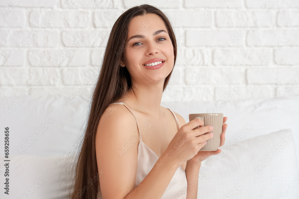 Morning of young woman drinking hot coffee in bed