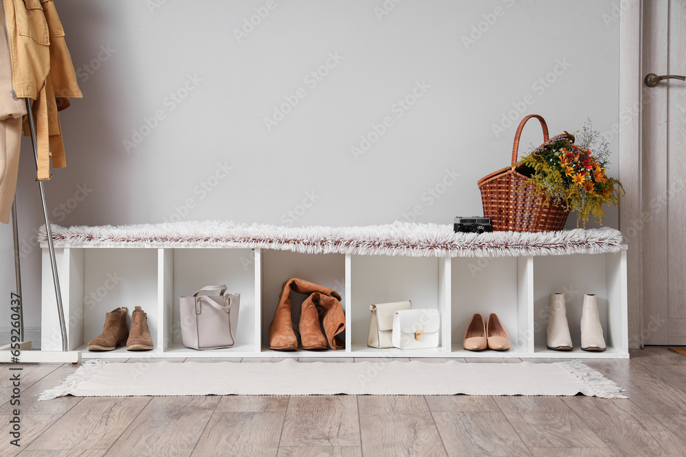 Interior of modern hallway with stylish shoes, purses and autumn flowers in wicker basket