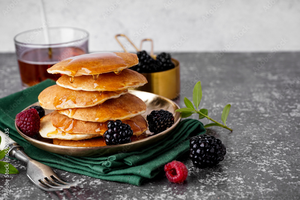 Plate of tasty pancakes with maple syrup and berries on table