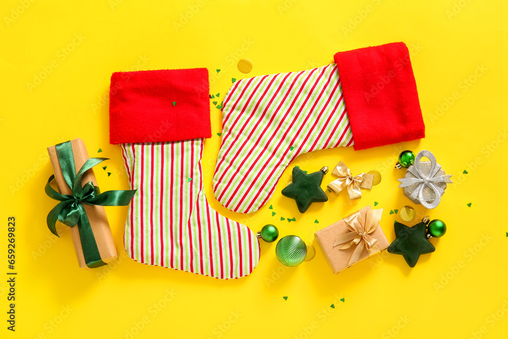 Christmas socks with beautiful decorations and gift boxes on yellow background