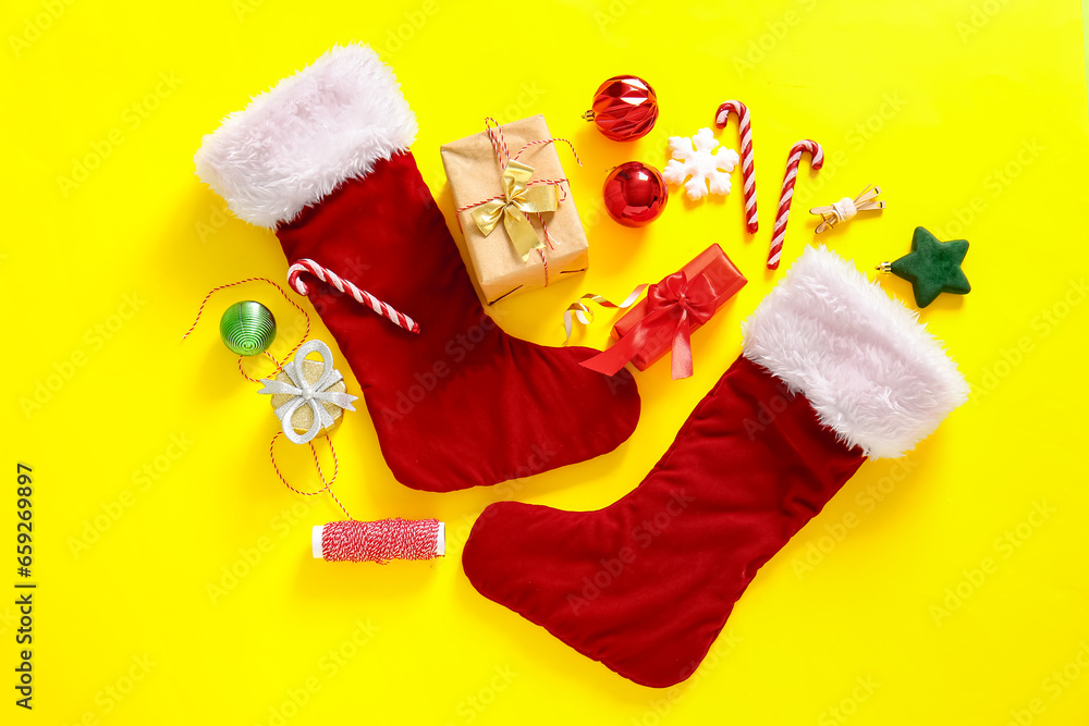 Christmas socks with beautiful decorations, candy canes and gift boxes on yellow background