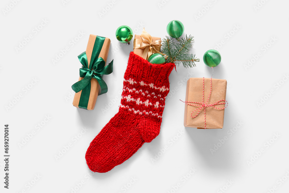 Christmas sock with balls and gift boxes on white background