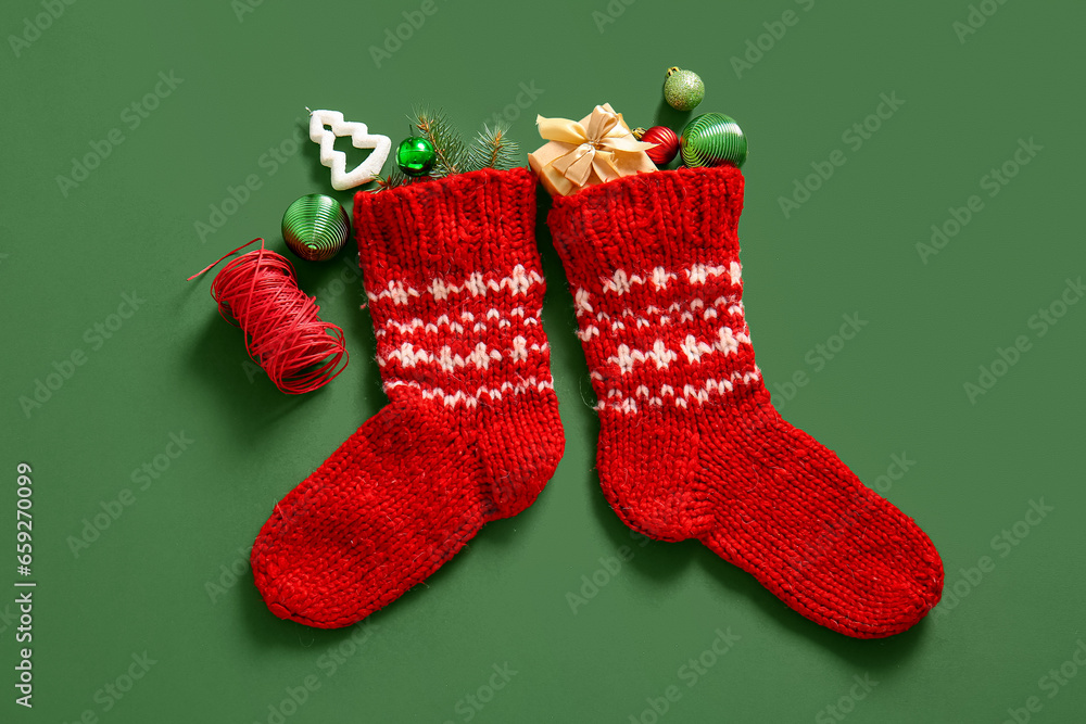 Christmas sock with beautiful decorations and gift box on green background