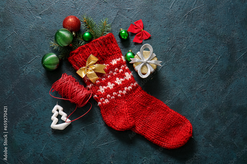 Christmas sock with tree branches, beautiful decorations and gift box on blue background