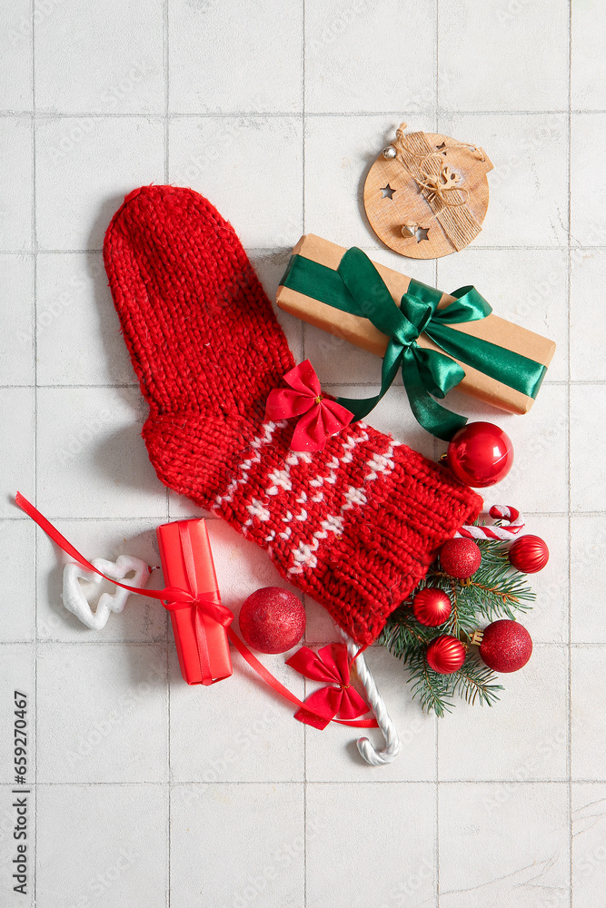 Christmas sock with tree branches, beautiful decorations and gift boxes on white tile background