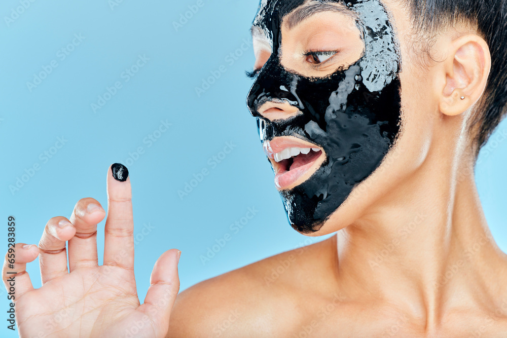 Skincare, charcoal mask and finger of woman for facial treatment, anti aging detox and wellness. Beauty, studio and person with face products for health, cosmetics or grooming on blue background