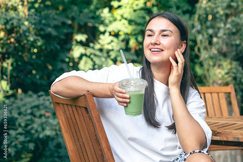 Woman drinking matcha latte while sitting at cafe outdoors.