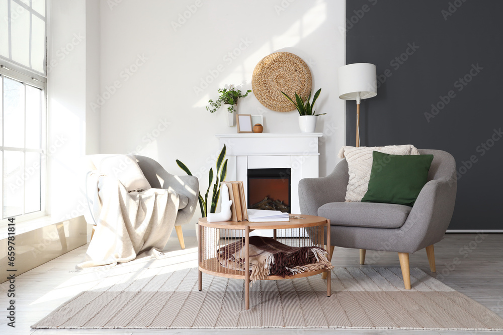 Interior of bright living room with armchairs, coffee table and fireplace