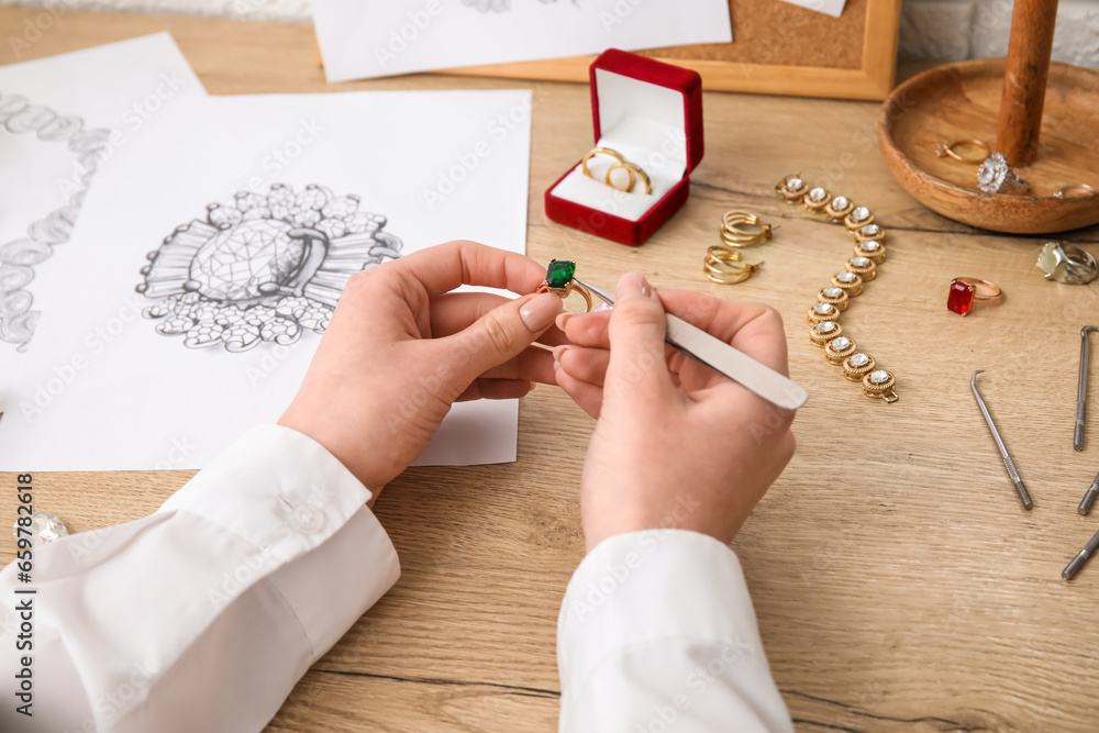 Female jeweler making ring on wooden table, closeup