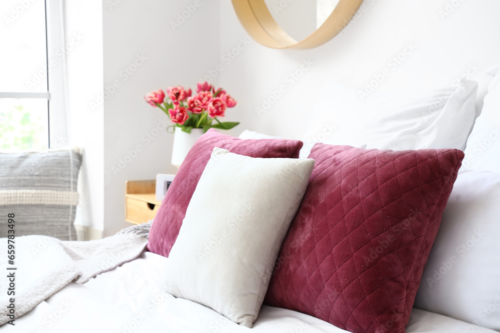 Soft pillows on bed in light bedroom, closeup