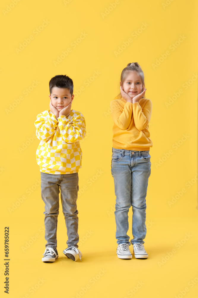 Cute little children in sweaters on yellow background