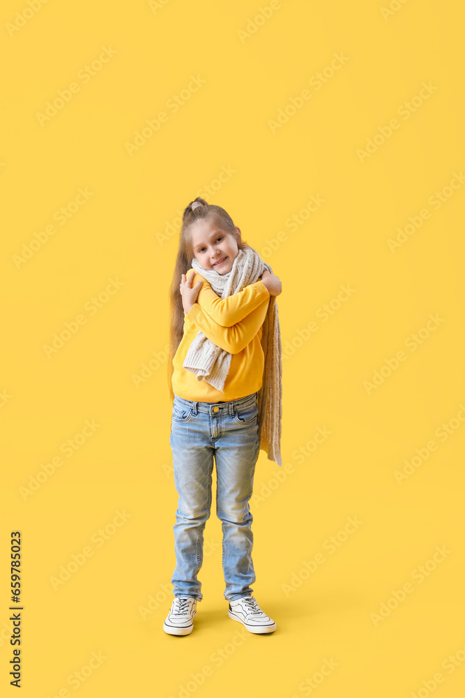 Cute little girl in sweater on yellow background