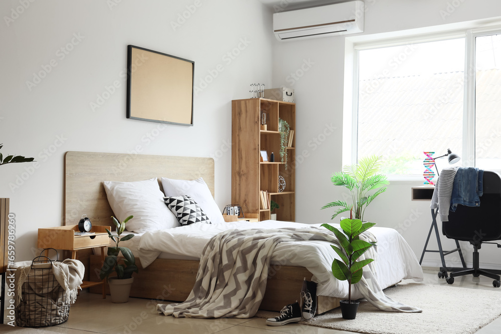 Interior of childrens bedroom with cozy bed, shelving unit, desk and houseplants